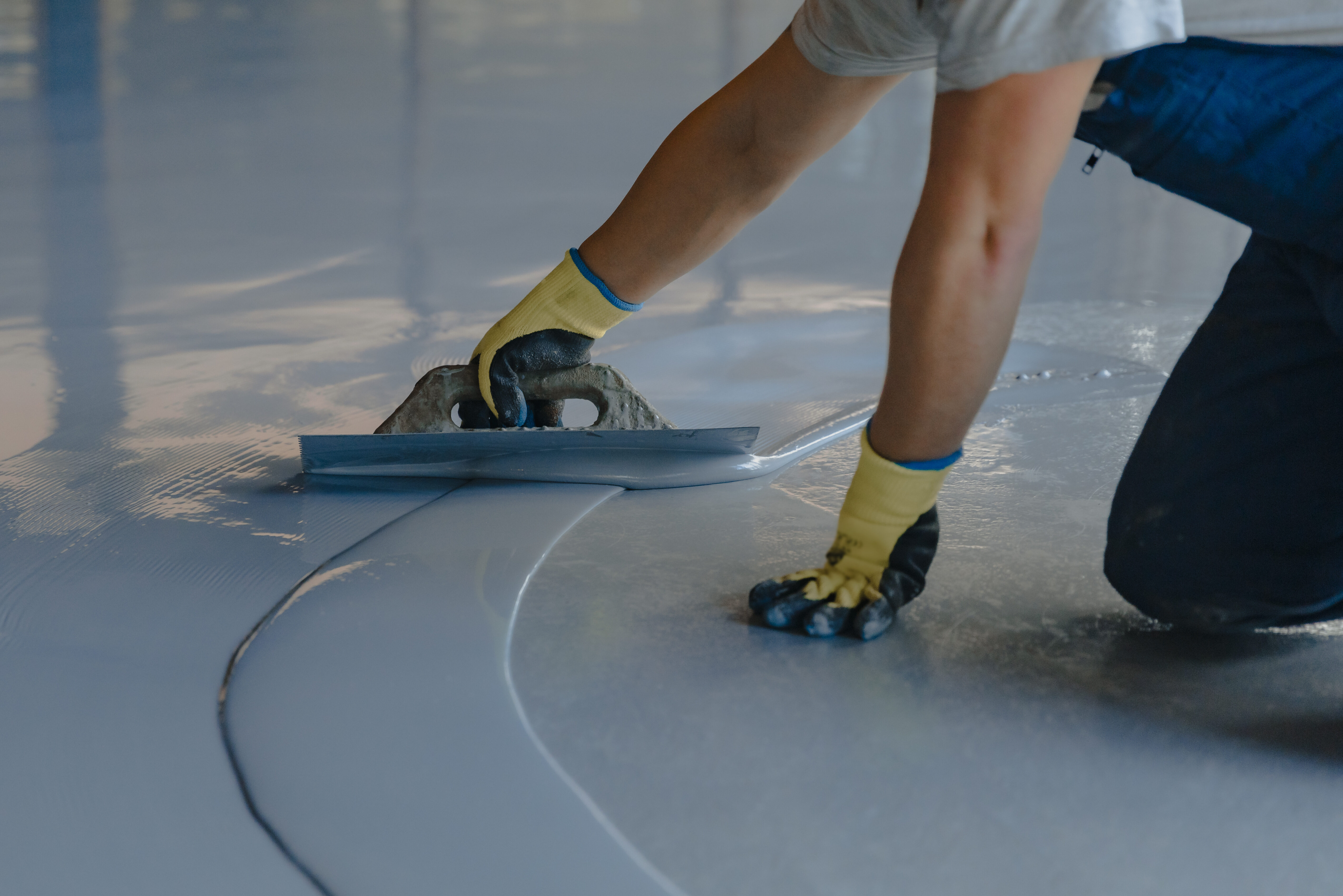 The worker applies gray epoxy resin to the new floor